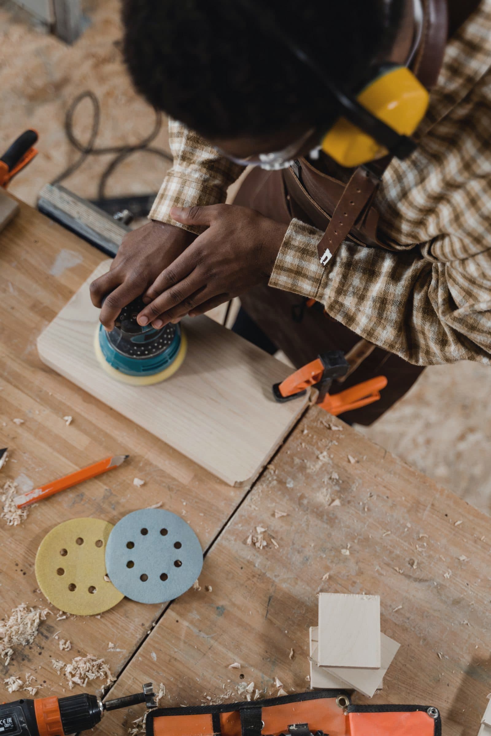 Carpenter sanding a timber panel in a workshop