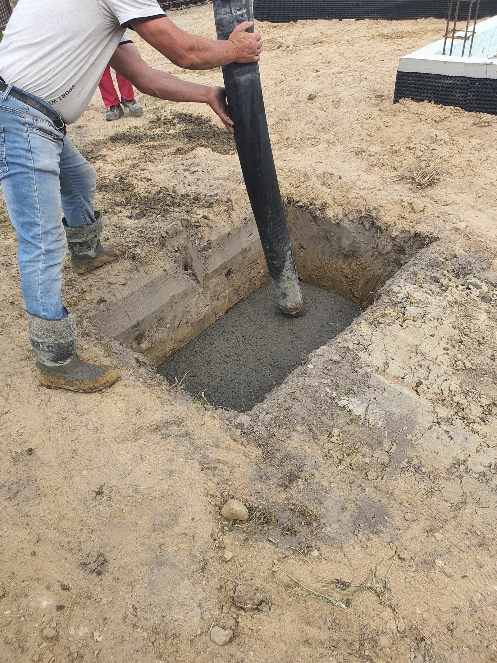 Worker pouring concrete into a foundation with a pump hose
