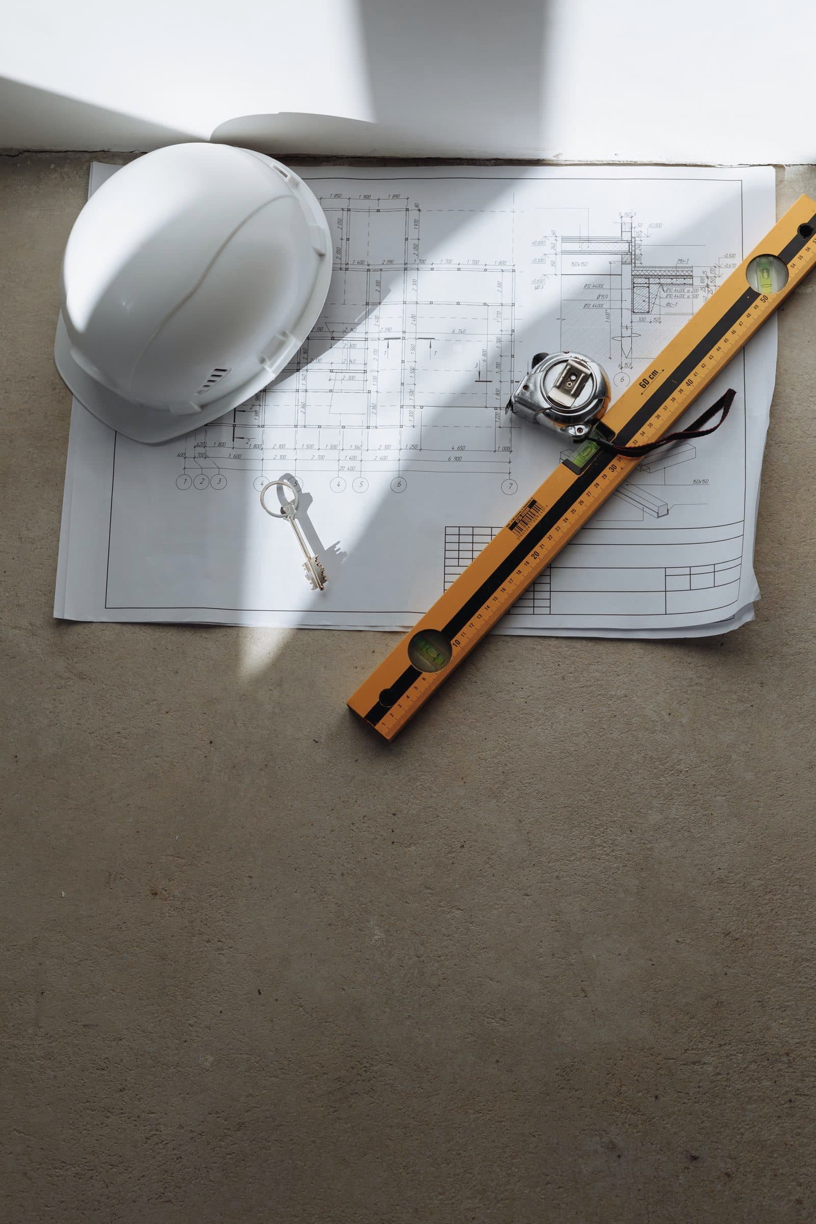 Construction plans with a hard hat, tape measure and level