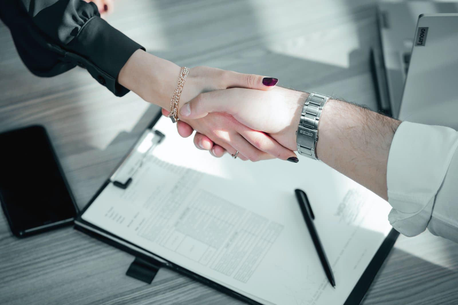 Handshake over a signed contract on a desk