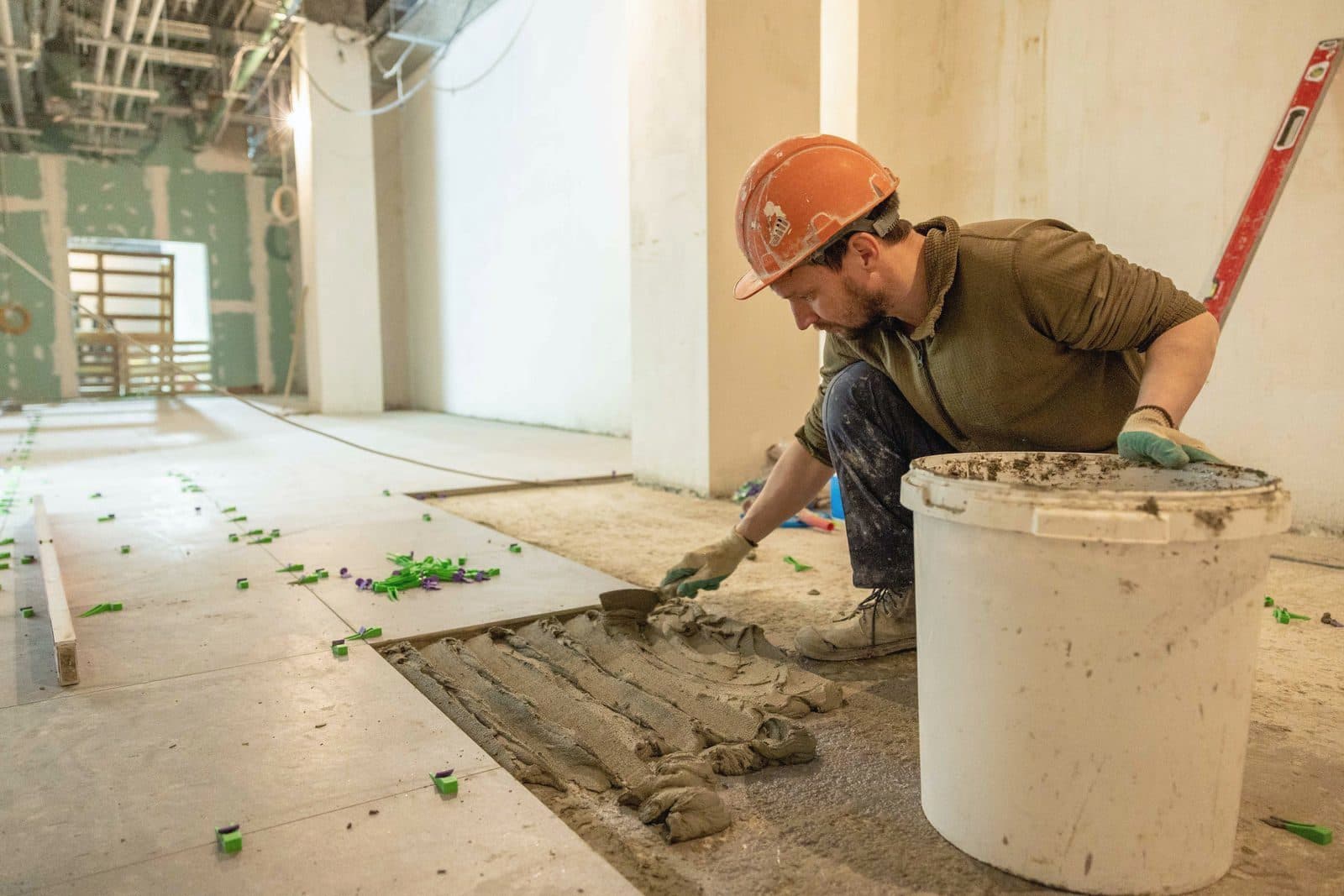 Tiler laying floor tiles indoors with mortar and trowel