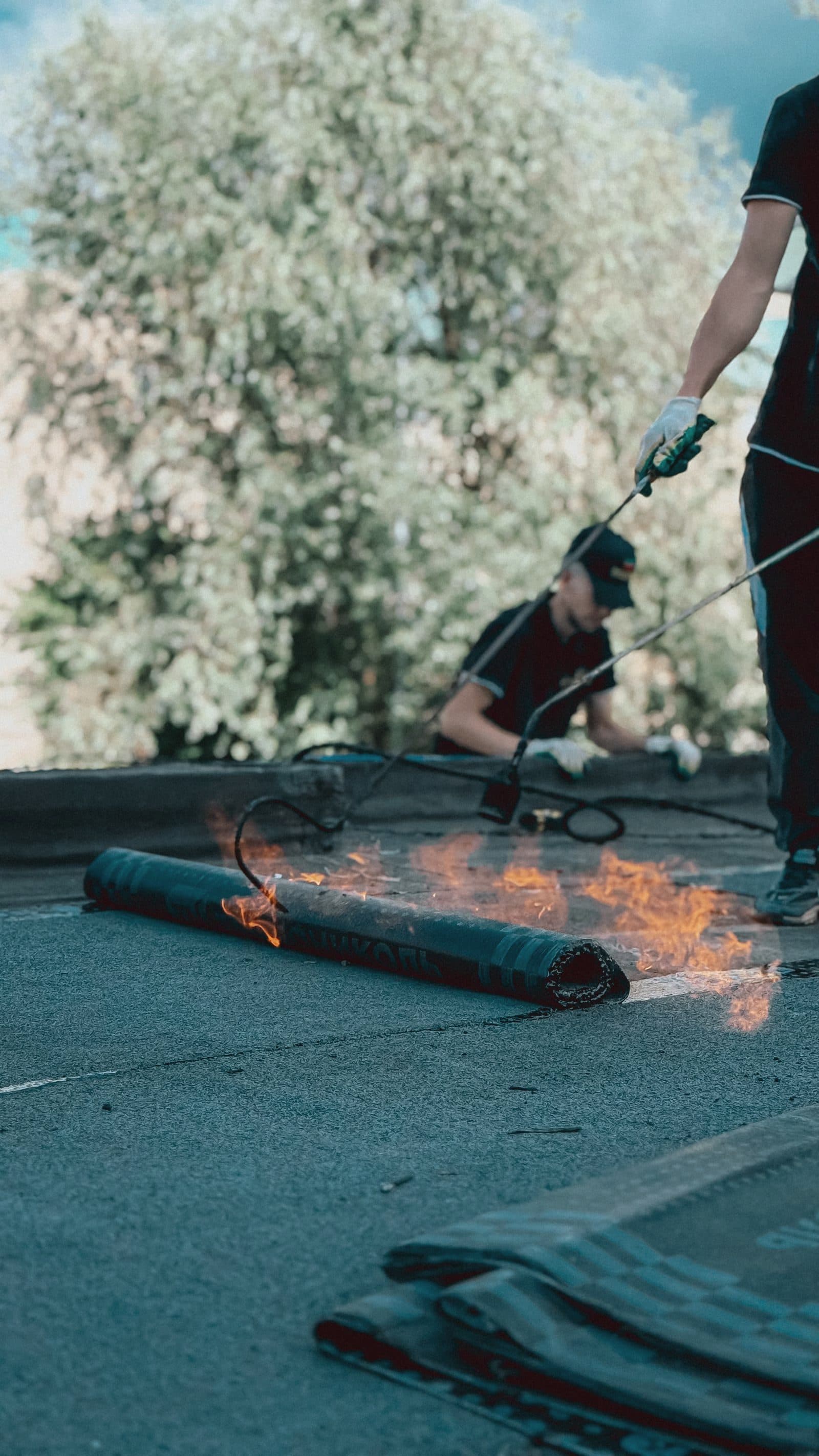 Roofers torching down a waterproofing membrane on a roof